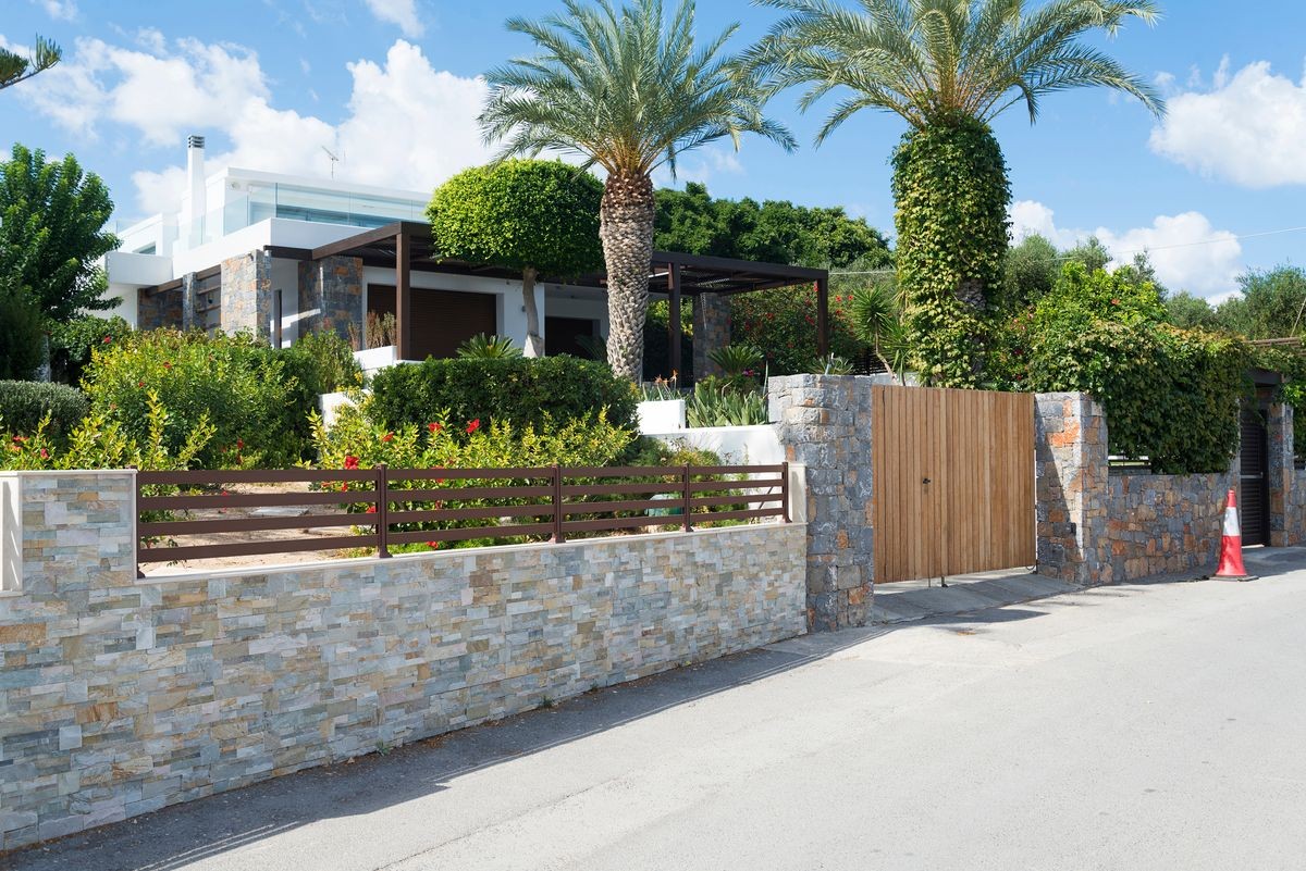 Modern country house with stone fence on the island of Crete, Greece. Sunny day.